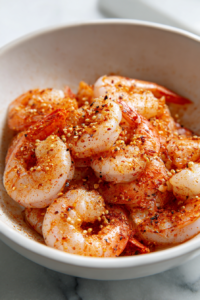 In a bowl, toss the shrimp with olive oil, chili powder, garlic powder, smoked paprika, onion powder, salt, and black pepper until evenly coated